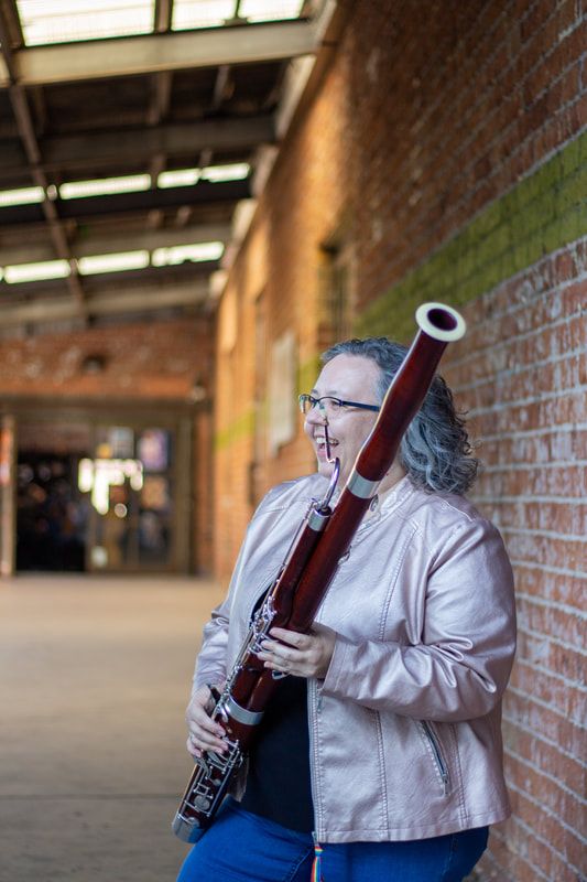 Cassandra Bendickson with Moosmann 200a Bassoon in front of a brick wall in downtown Tucson, photo by Mindi Rey Acosta